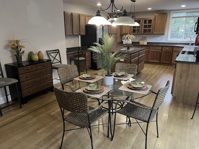 dining space featuring a notable chandelier, sink, and light hardwood / wood-style flooring