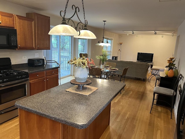 kitchen featuring light wood-type flooring, decorative light fixtures, a kitchen island, and gas range