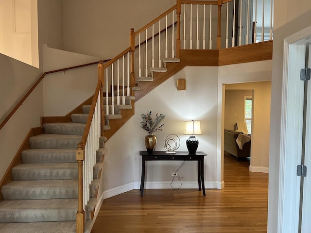 stairs with hardwood / wood-style flooring and a towering ceiling