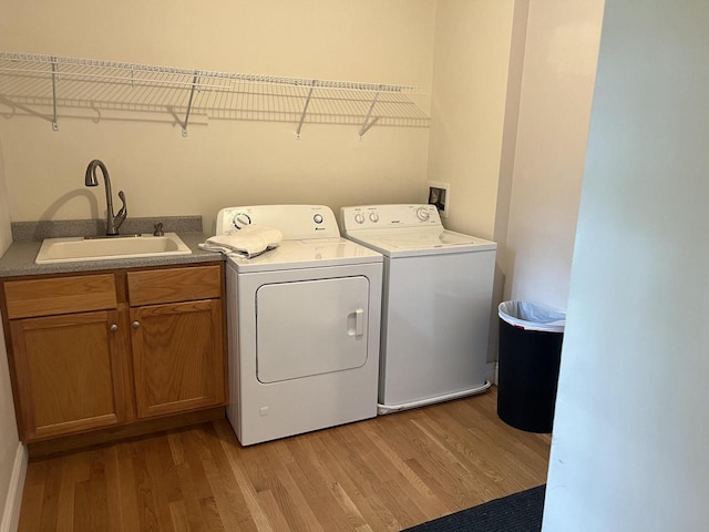 laundry area featuring washing machine and dryer, sink, and light hardwood / wood-style floors