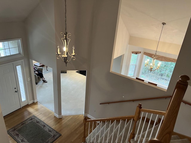 entryway with wood-type flooring, an inviting chandelier, and high vaulted ceiling