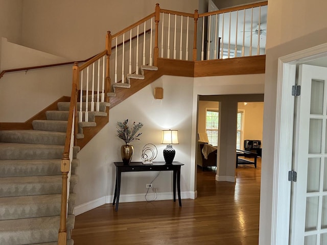 stairway featuring a high ceiling and hardwood / wood-style floors