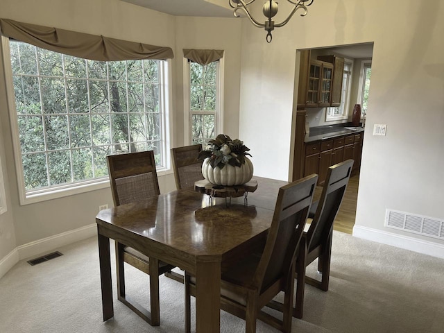 dining space with a notable chandelier, plenty of natural light, and carpet flooring