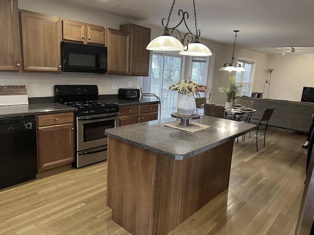 kitchen with hanging light fixtures, a chandelier, black appliances, a center island, and light hardwood / wood-style floors