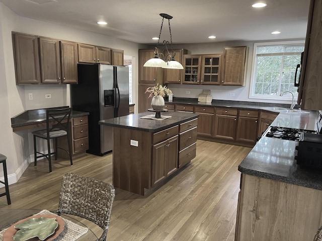 kitchen with a center island, sink, hanging light fixtures, light hardwood / wood-style flooring, and stainless steel refrigerator with ice dispenser