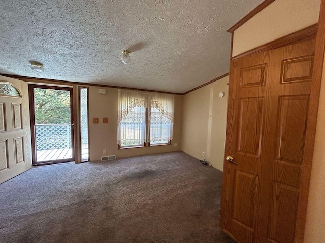 interior space featuring ornamental molding, dark colored carpet, and a textured ceiling