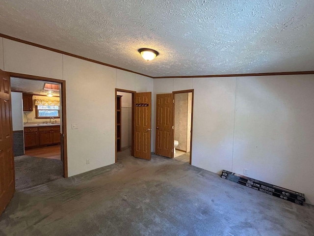 unfurnished bedroom with lofted ceiling, sink, ensuite bathroom, carpet, and a textured ceiling