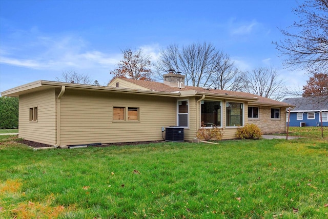 rear view of house with central air condition unit and a lawn