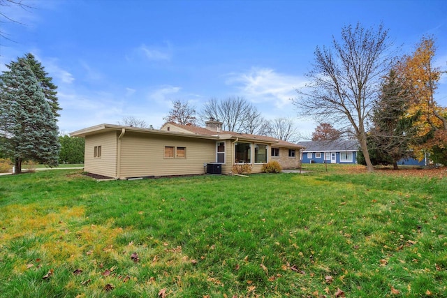 back of house with cooling unit and a lawn