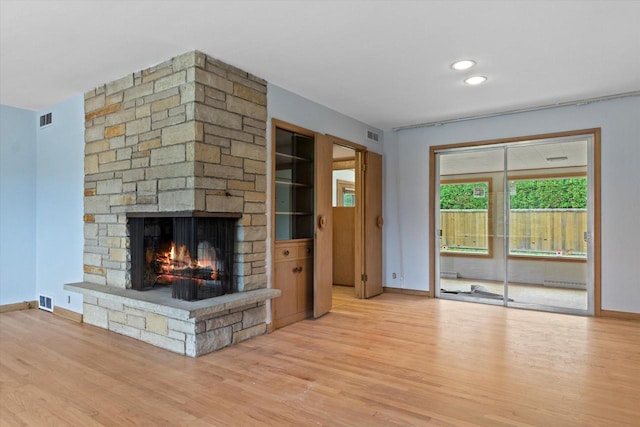 unfurnished living room with a stone fireplace and light hardwood / wood-style floors