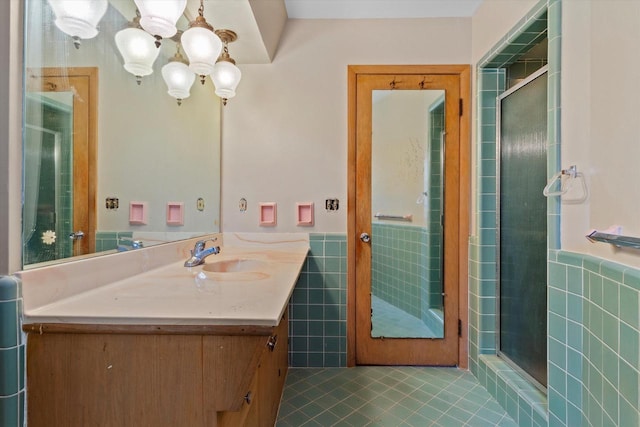 bathroom featuring tile patterned flooring, vanity, a shower with door, and tile walls