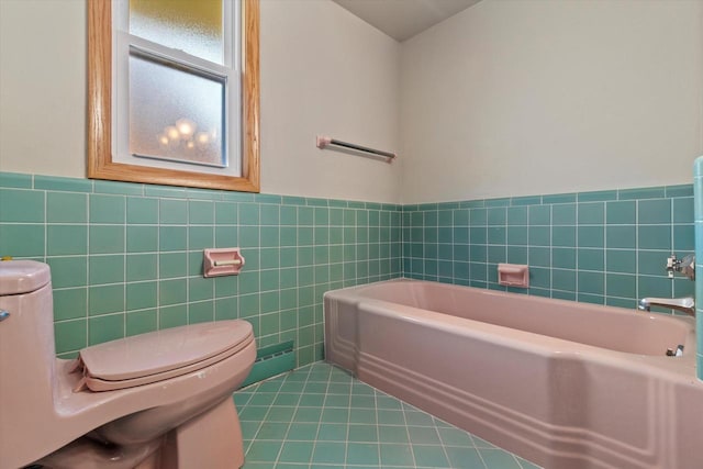 bathroom with tile walls, toilet, a tub to relax in, and tile patterned floors