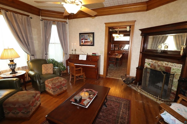 living room with crown molding, ceiling fan with notable chandelier, hardwood / wood-style floors, and a tile fireplace