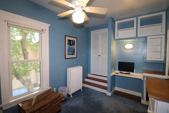 office featuring ceiling fan, radiator heating unit, and dark colored carpet