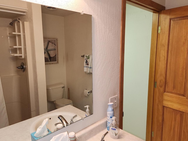 bathroom featuring vanity, walk in shower, and toilet