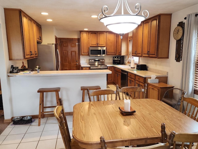 kitchen featuring light tile patterned floors, kitchen peninsula, decorative light fixtures, black appliances, and a notable chandelier