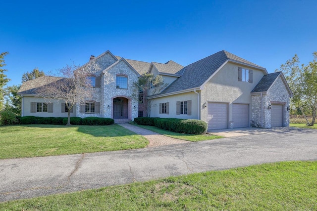 french country style house featuring a front yard and a garage