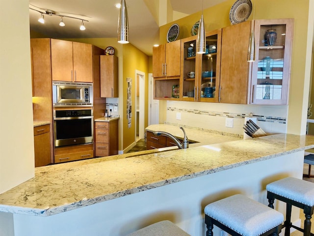 kitchen with stainless steel appliances, kitchen peninsula, pendant lighting, and a breakfast bar