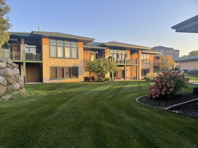 back of house featuring a balcony and a yard