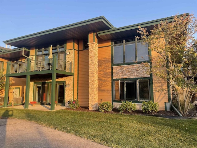 back of house featuring cooling unit, a balcony, a yard, and a patio