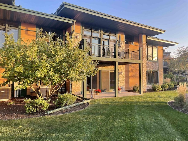 rear view of house featuring central air condition unit, a patio, a yard, and a balcony