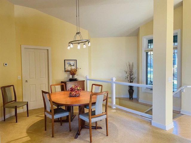 dining room featuring light colored carpet, an inviting chandelier, and lofted ceiling