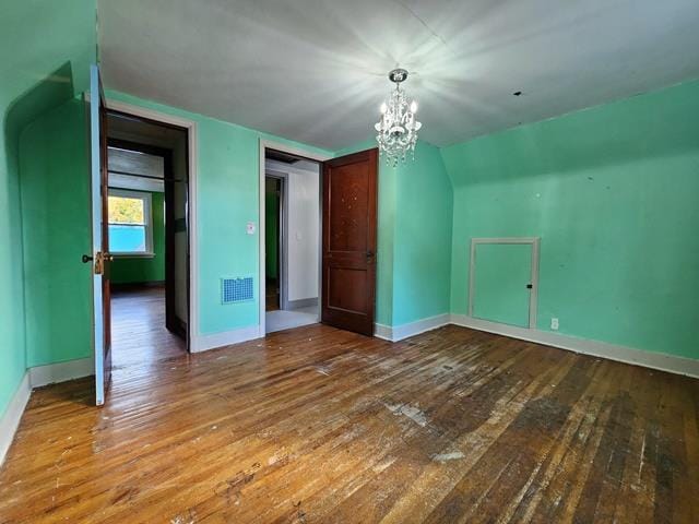 bonus room with wood-type flooring, lofted ceiling, and a chandelier