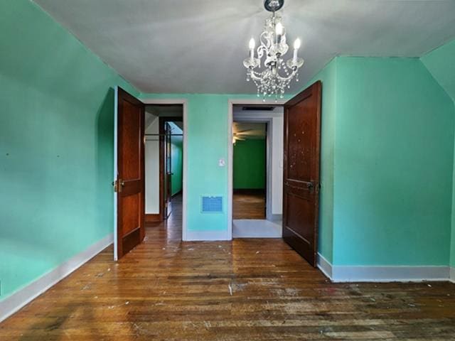 unfurnished bedroom with dark wood-type flooring and a notable chandelier