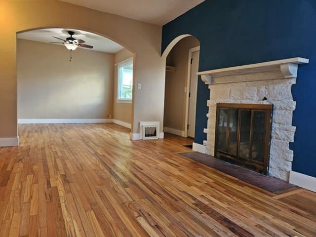 unfurnished living room with light wood-type flooring, a fireplace, and ceiling fan