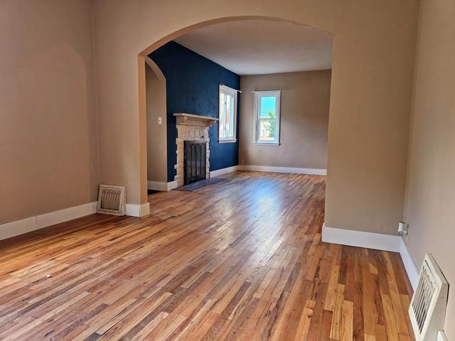 unfurnished living room featuring a stone fireplace and wood-type flooring