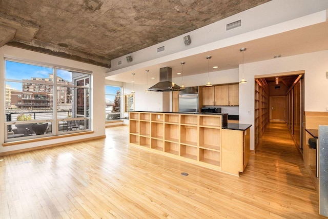 kitchen with island range hood, a wealth of natural light, light hardwood / wood-style flooring, pendant lighting, and built in refrigerator