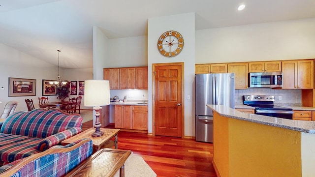 kitchen with an inviting chandelier, hanging light fixtures, stainless steel appliances, high vaulted ceiling, and dark hardwood / wood-style flooring