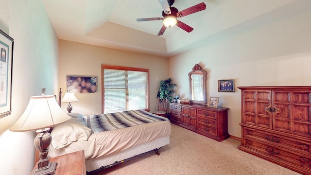 bedroom featuring light carpet, ceiling fan, and a tray ceiling