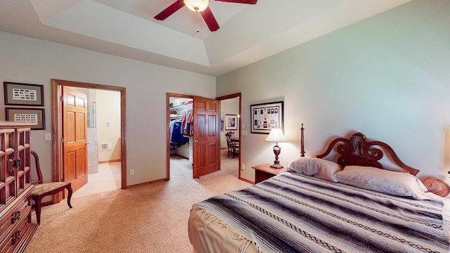 carpeted bedroom featuring ceiling fan, connected bathroom, a raised ceiling, a walk in closet, and a closet