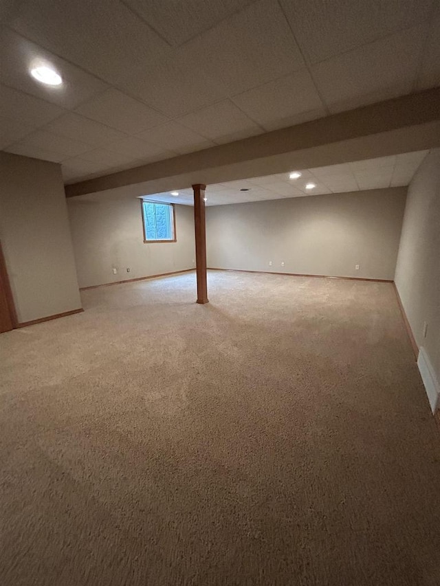 basement featuring a drop ceiling and carpet