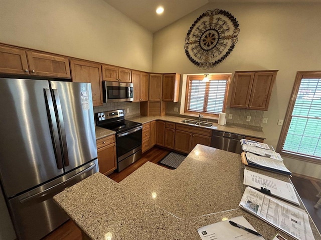 kitchen featuring sink, backsplash, stainless steel appliances, high vaulted ceiling, and light stone counters