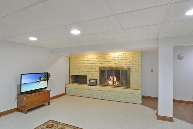 living room featuring a fireplace, a drop ceiling, and carpet