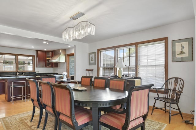 dining space featuring a notable chandelier, sink, light hardwood / wood-style flooring, and a healthy amount of sunlight