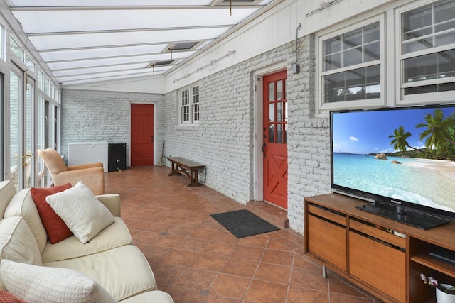 living room featuring lofted ceiling, brick wall, and dark tile patterned flooring