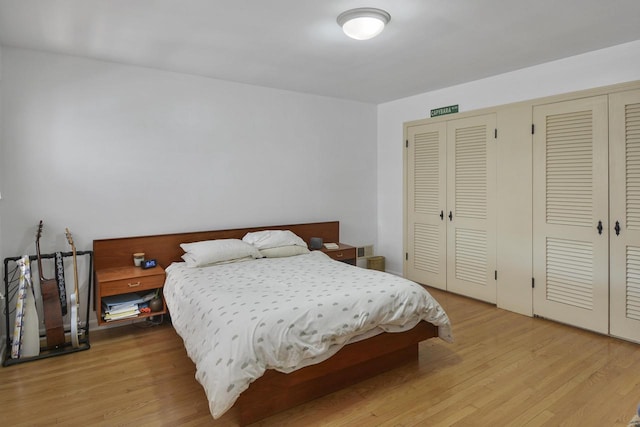 bedroom with light hardwood / wood-style flooring and two closets