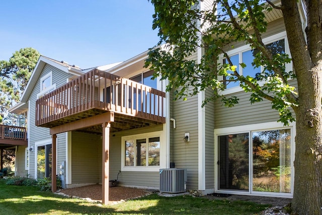 rear view of house featuring central air condition unit, a deck, and a lawn