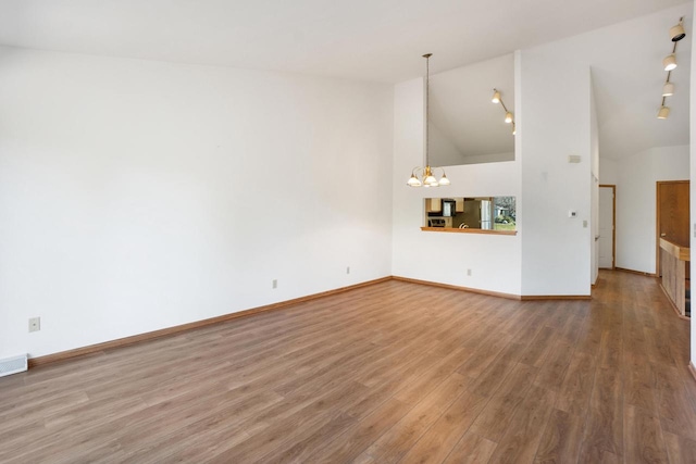 unfurnished living room featuring a notable chandelier, hardwood / wood-style flooring, and high vaulted ceiling