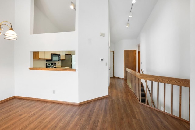 hall with hardwood / wood-style flooring, track lighting, and high vaulted ceiling