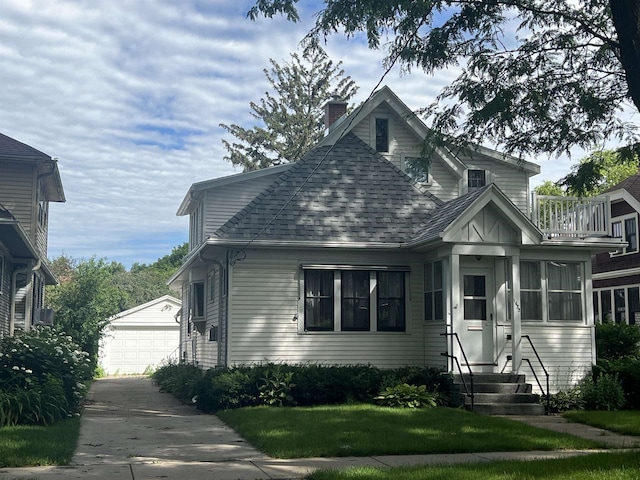 bungalow-style house with a front yard, a garage, and an outdoor structure