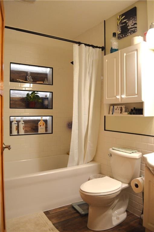 full bathroom featuring hardwood / wood-style floors, tile walls, toilet, vanity, and shower / tub combo with curtain