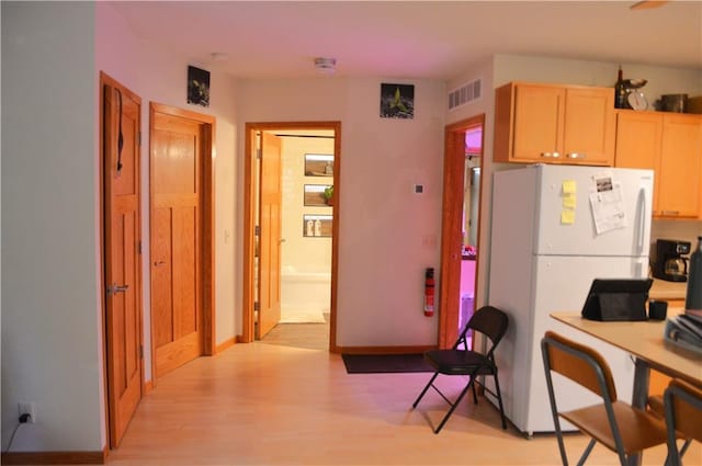 kitchen with light hardwood / wood-style flooring, light brown cabinetry, and white refrigerator