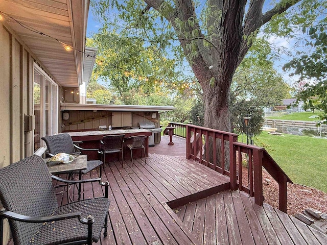 wooden terrace featuring a yard, a grill, and a water view