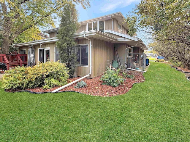 view of side of home with a deck and a lawn