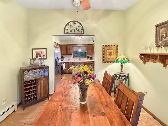 dining room featuring light hardwood / wood-style floors, a baseboard heating unit, sink, and ceiling fan