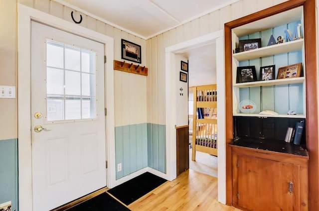 doorway to outside with wooden walls and light wood-type flooring